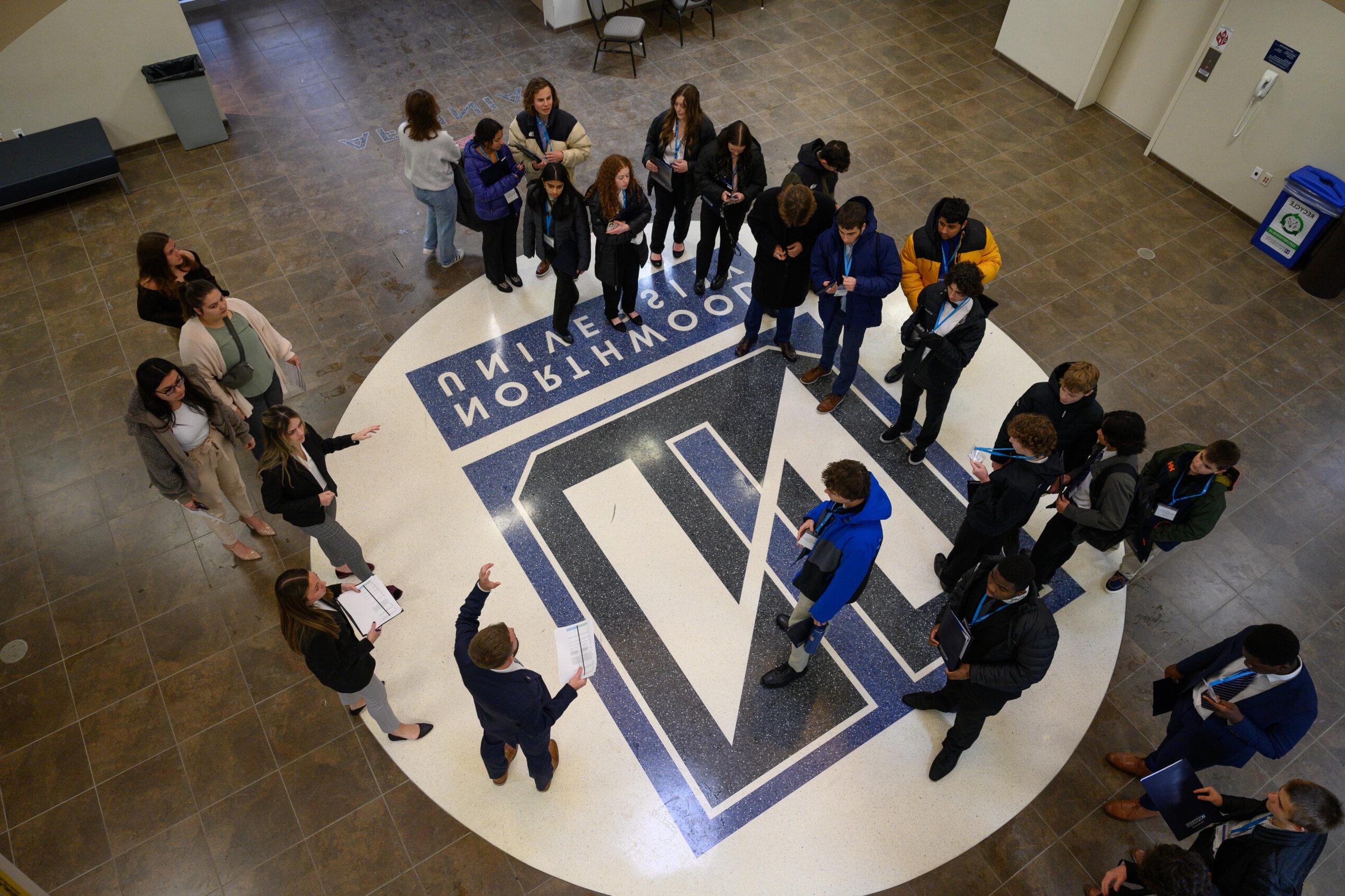 Group of students gathered around the Northwood logo for DECA Day